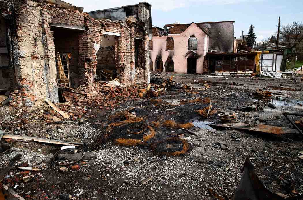 Severely fire-damaged brick buildings with collapsed walls and scorched debris on the ground.