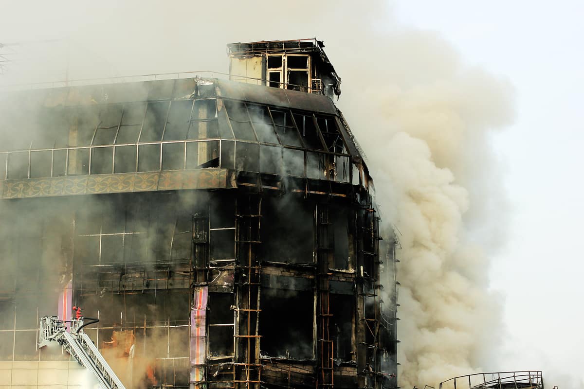 Severe commercial fire damage showing a blackened building structure engulfed in thick smoke.