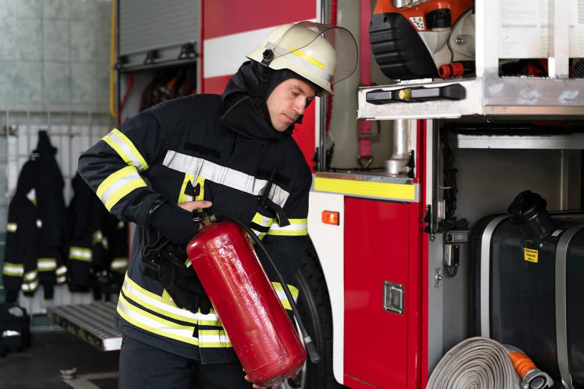 Firefighter with fire extinguisher standing beside an emergency response vehicle