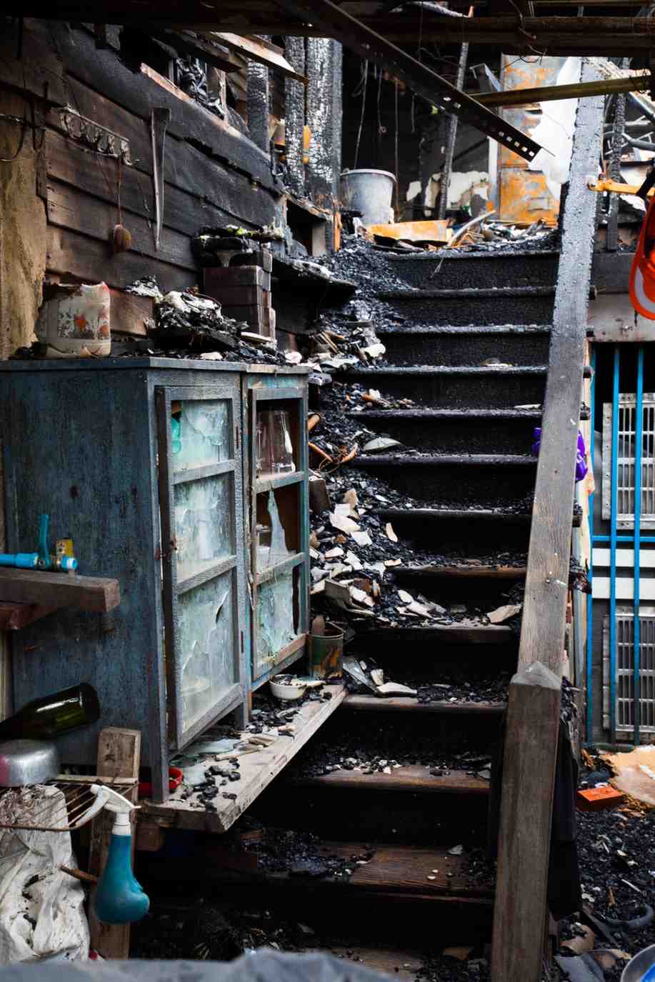 Charred staircase and heavy soot debris inside a home after a severe house fire.