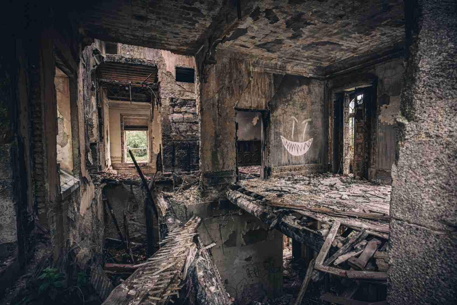 Severe interior fire damage showing a collapsed floor, charred walls, and structural debris.