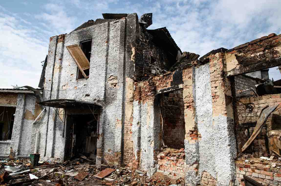 Water and fire damaged brick building with collapsed walls.