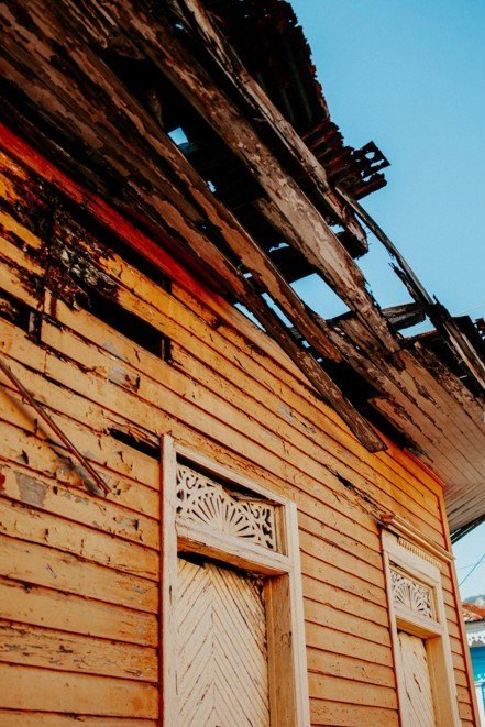 Destroyed and charred wooden roof on a yellow exterior house indicating severe fire damage.