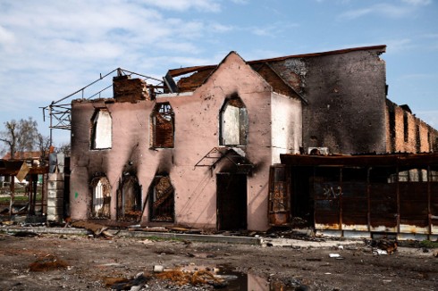 Exterior of a large building devastated by structural fire damage, showing a collapsed roof and soot.