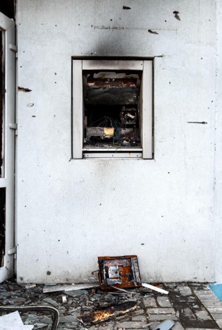 Close-up of intense fire damage showing a gutted wall unit, heavy smoke stains, and charred debris.
