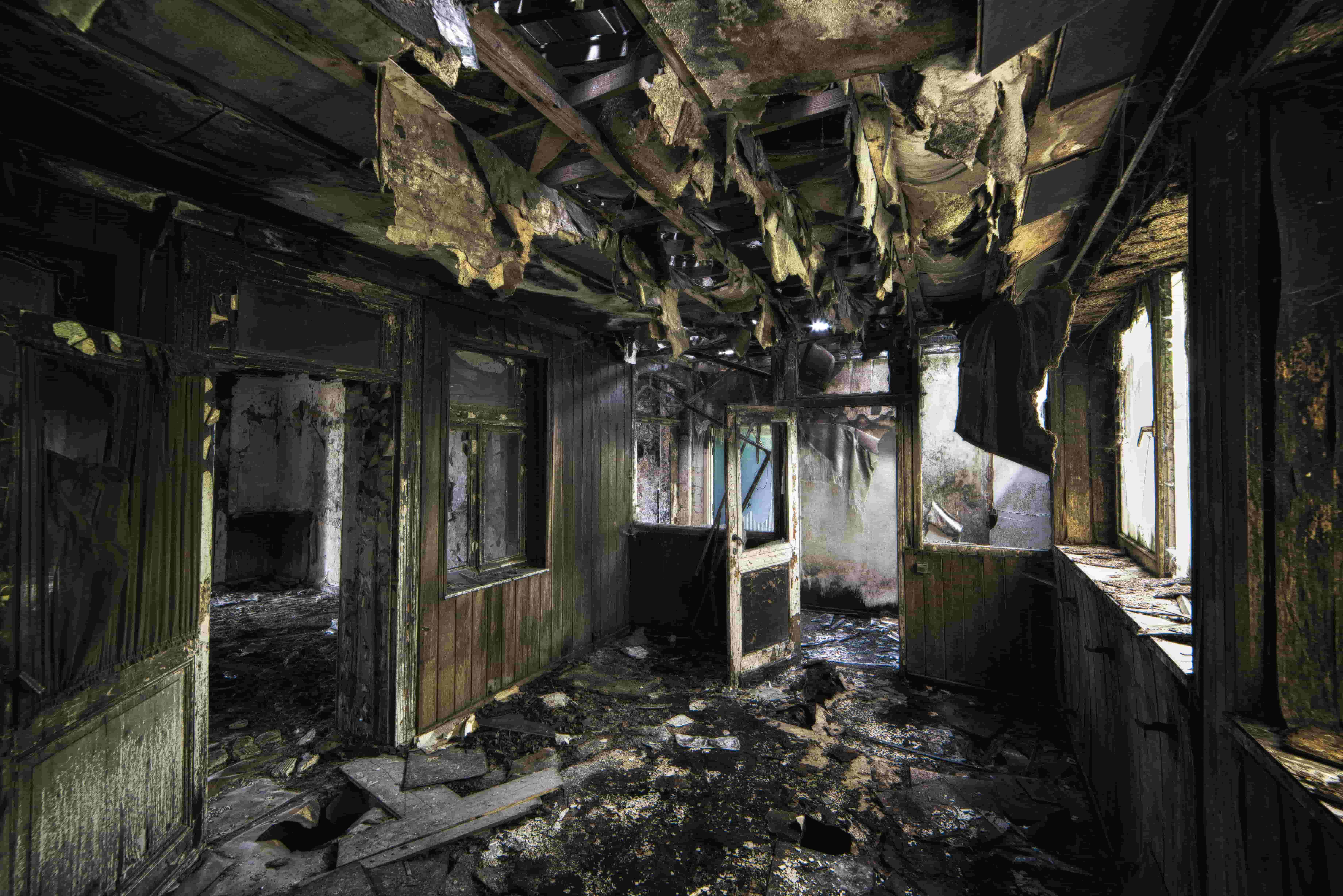 Severely fire-damaged building interior with charred walls and collapsed ceiling