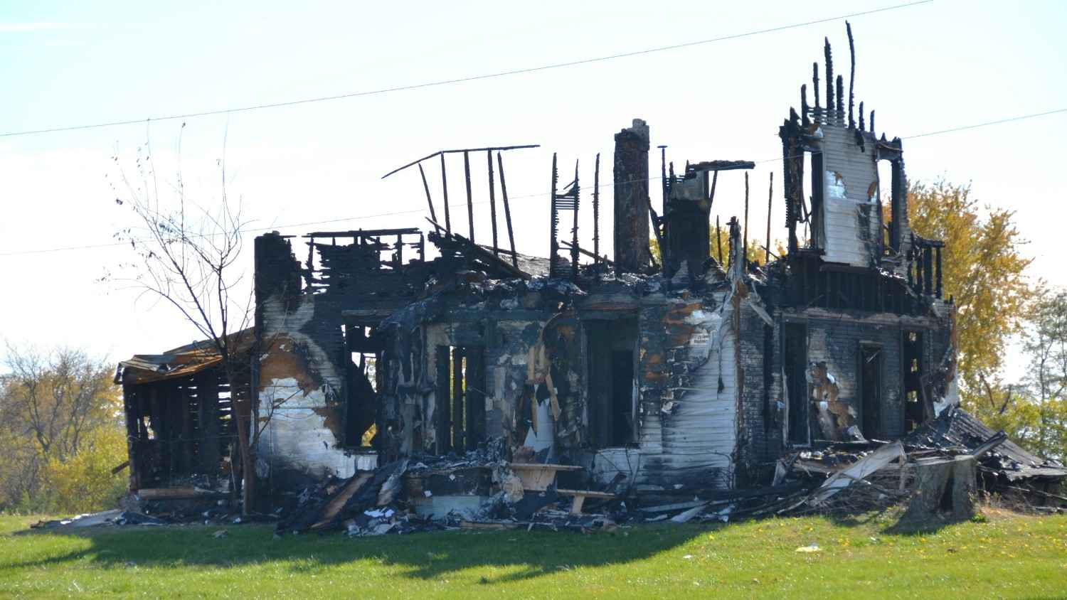 Total loss residential property showing a completely charred frame after a severe house fire.
