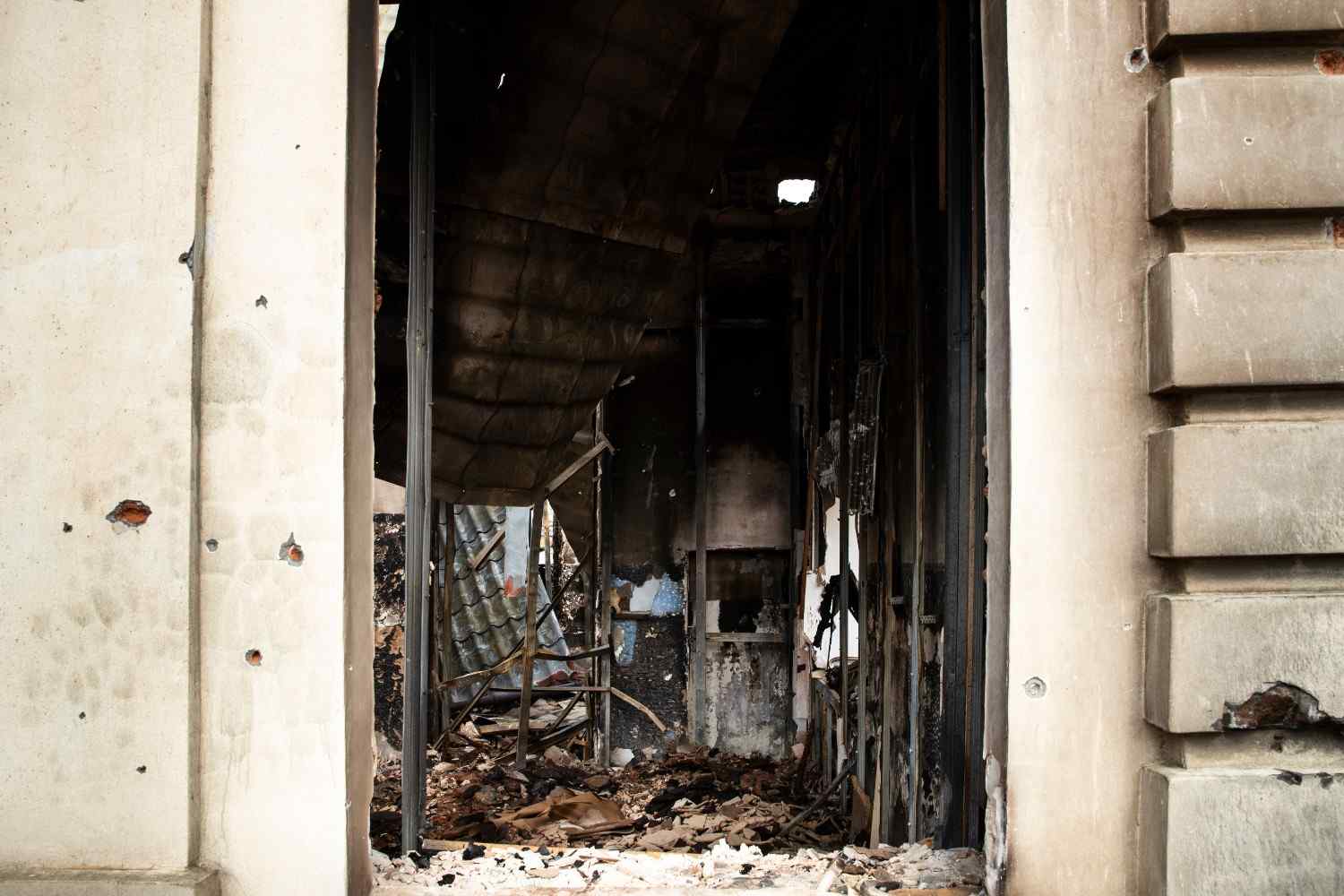 Charred interior and rubble seen through the doorway of a severely fire-damaged building needing restoration.