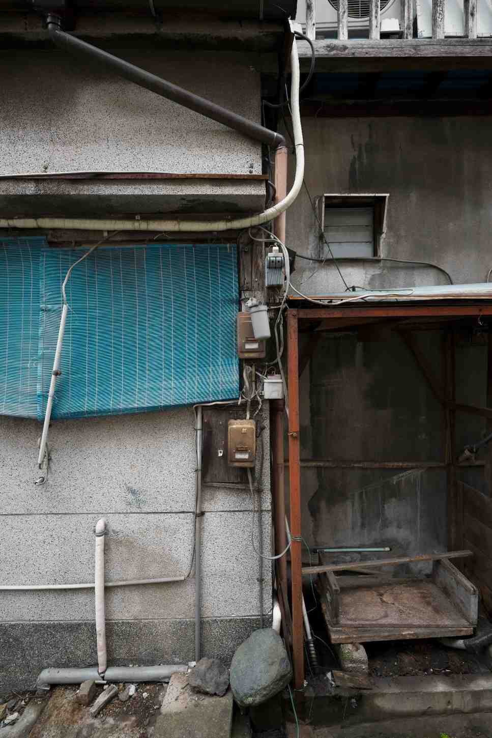 Exterior wall of an abandoned house with exposed wires and heavy damage, illustrating structural fire risks.