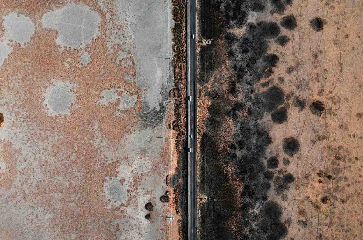 Aerial view of a straight highway cutting through contrasting desert terrain.