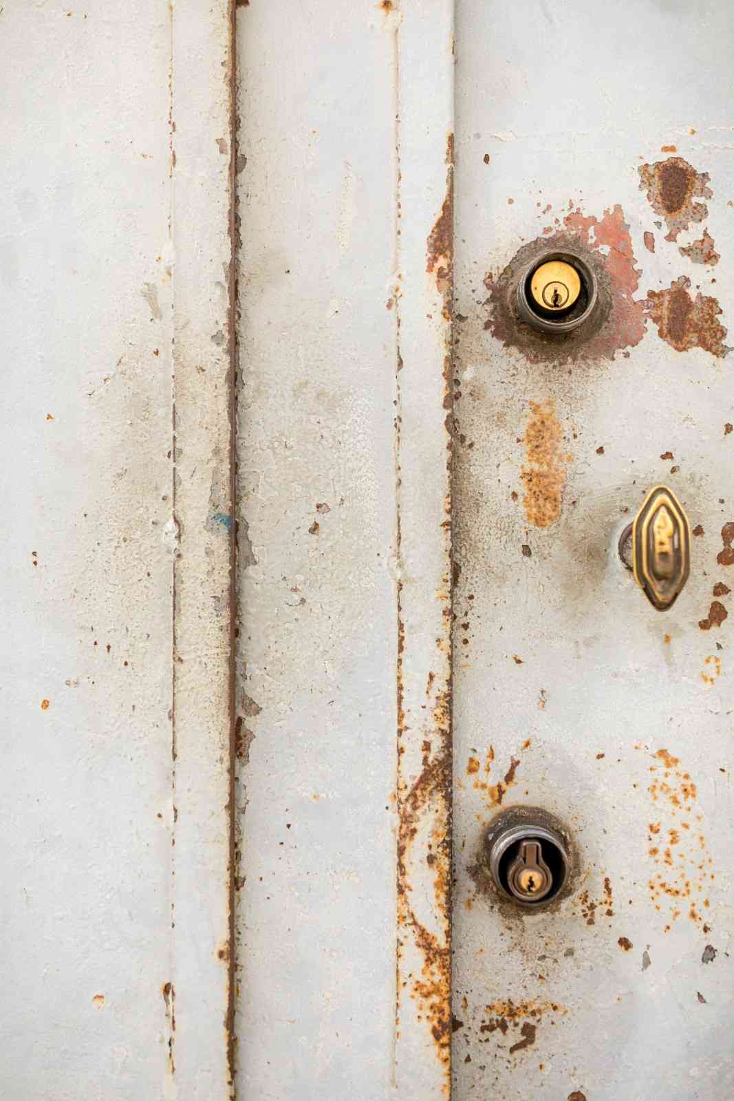 Deteriorating metal structure with locks, showing extensive surface decay and prolonged water damage.