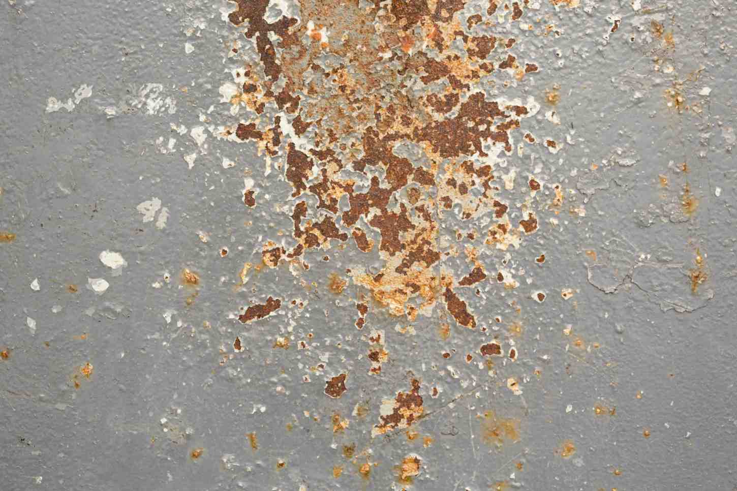 Weathered grey steel wall texture with scratches, flaking paint, and spots of rust corrosion.