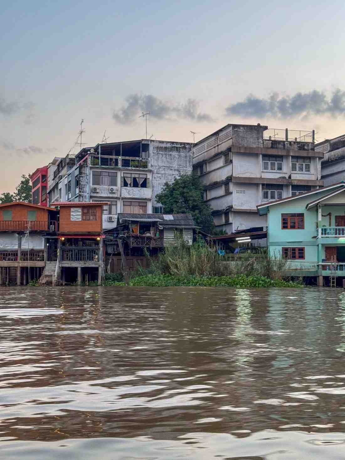 Waterfront buildings and homes built closely along a flooded, brown river.