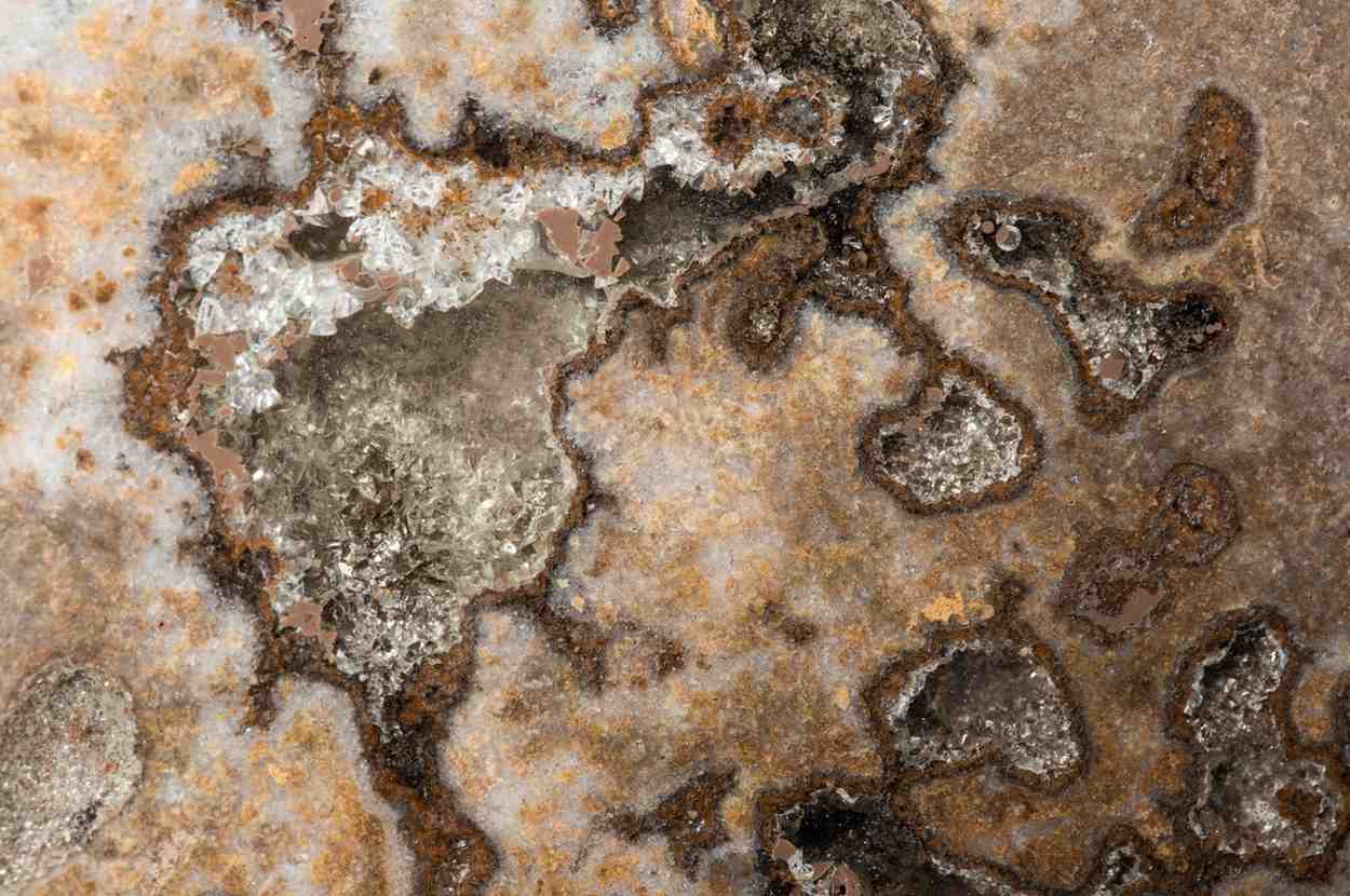 Heavy mineral deposits, rust, and efflorescence deteriorating a stone surface from a water leak.