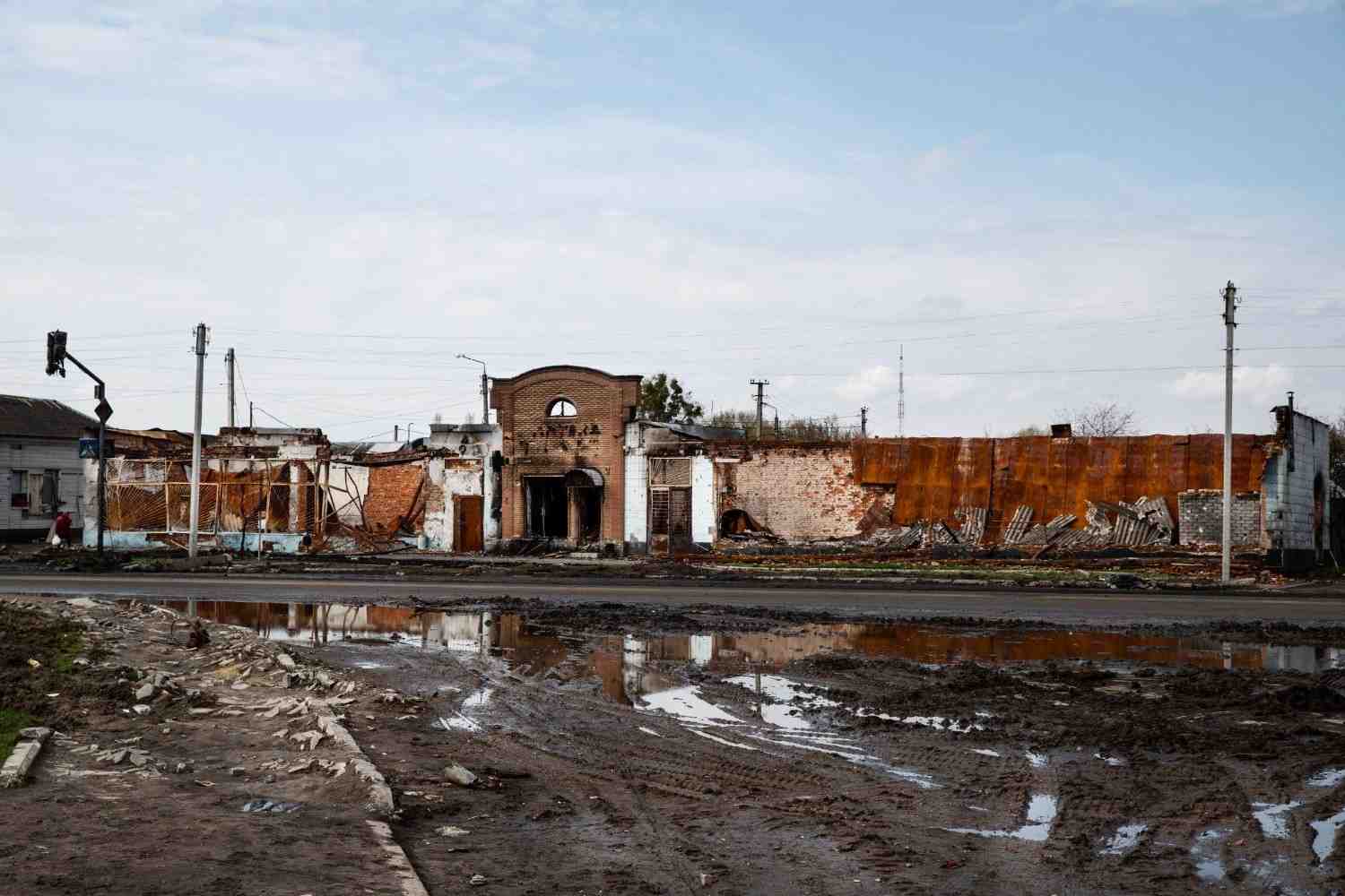 Large puddles of standing flood water pooling in front of a heavily damaged building.