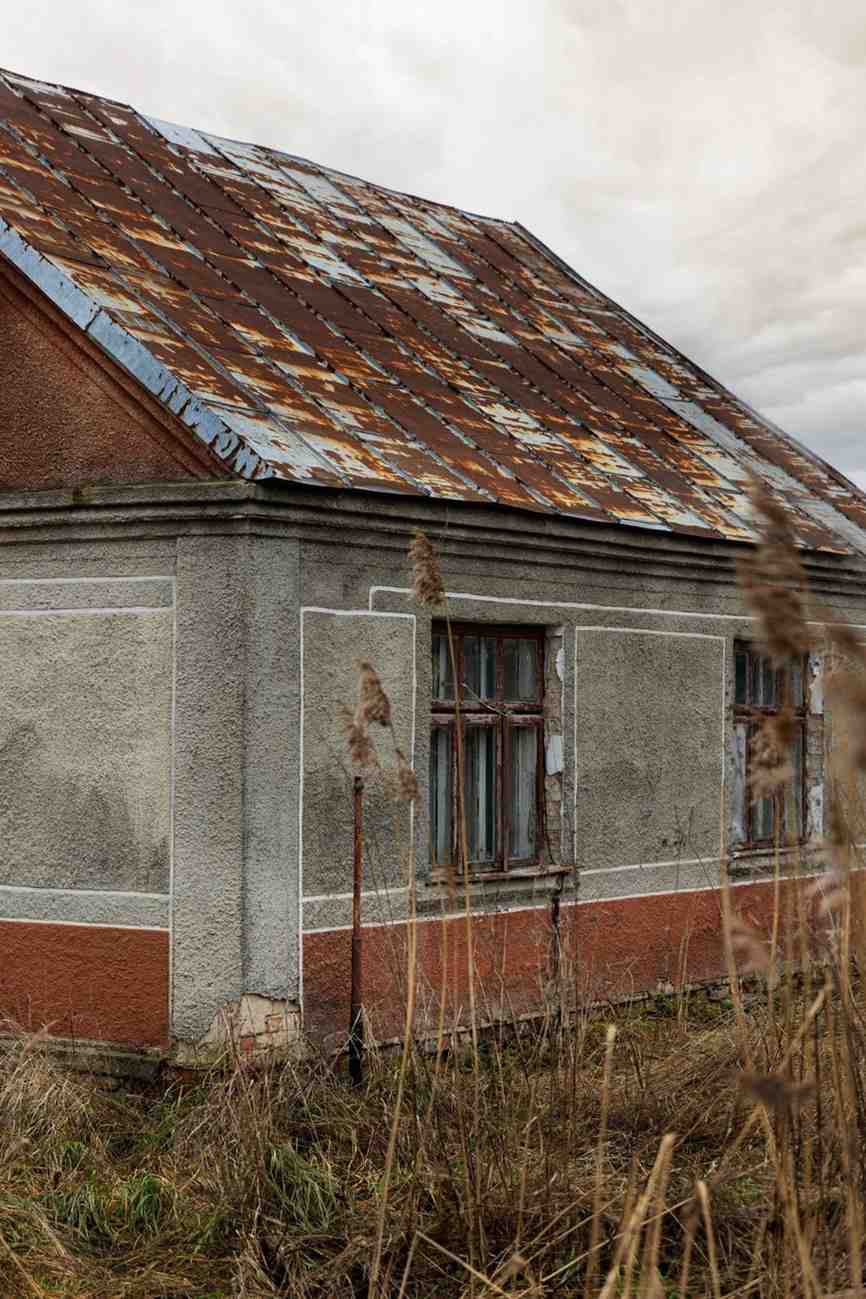 Rusted metal roof and moisture-stained walls on an old weathered house.