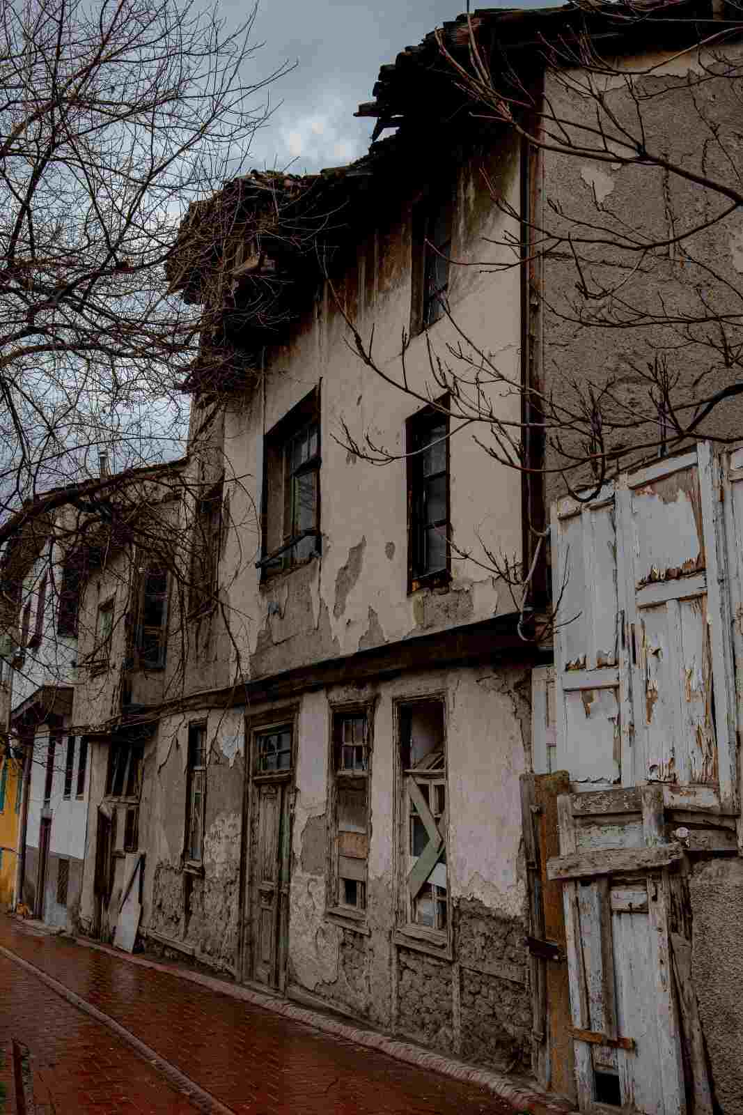 Old building exterior showing severe peeling plaster and structural decay from water damage.