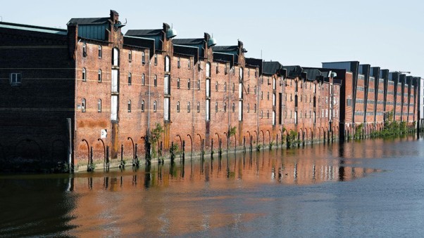 High floodwaters pressing against commercial brick building foundations causing water damage.
