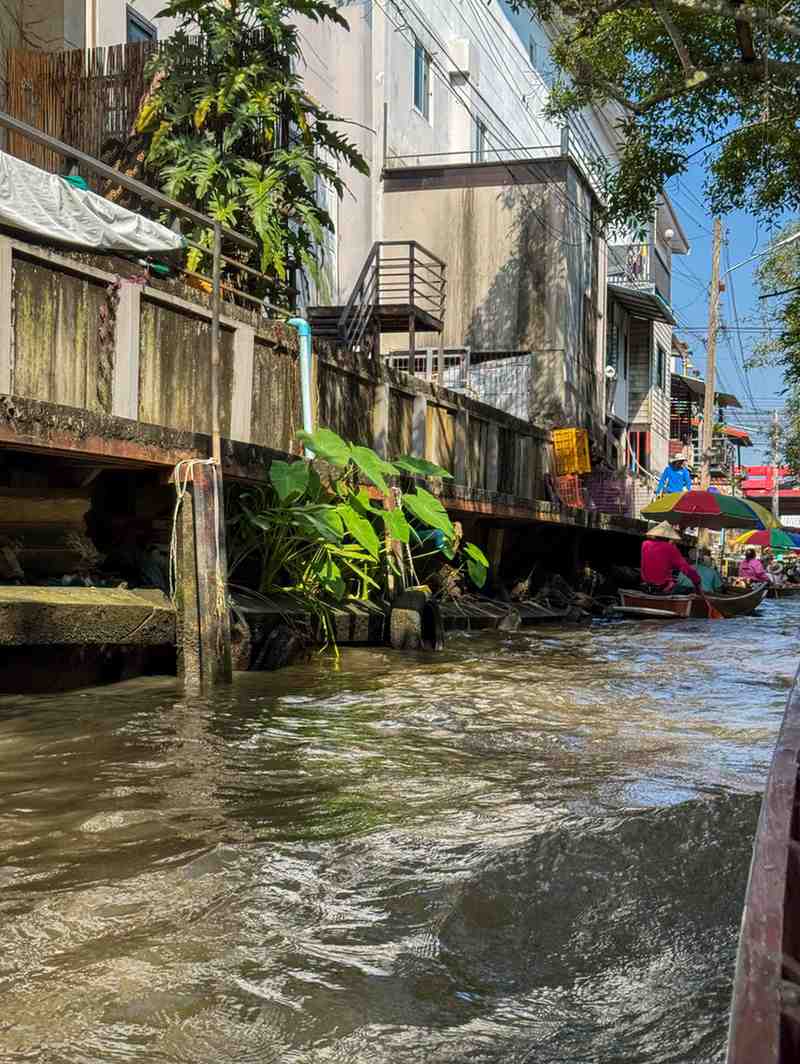 High water levels in an urban waterway flowing directly against the vulnerable concrete foundations of residential buildings