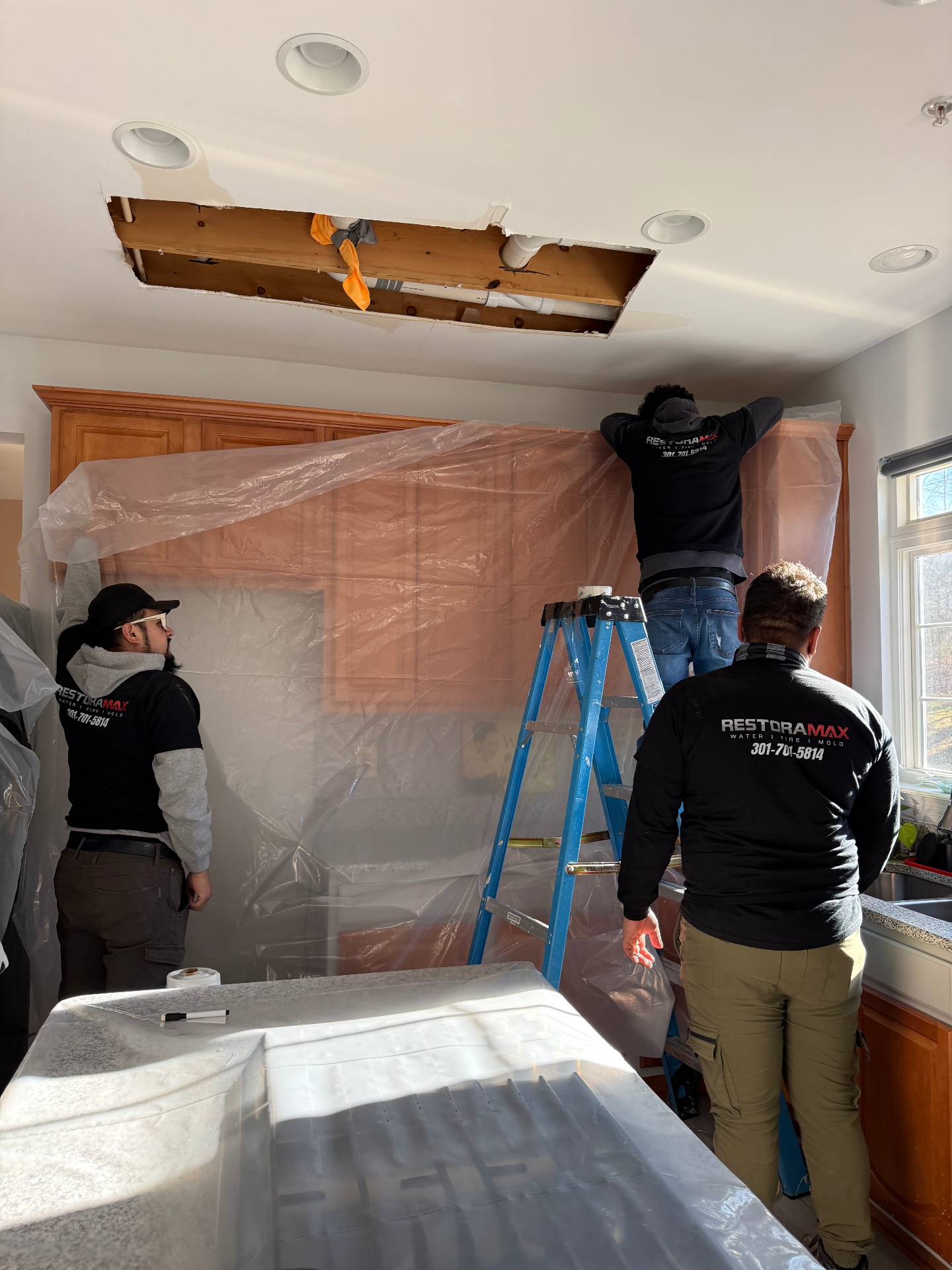 Crew repairing ceiling water damage in kitchen