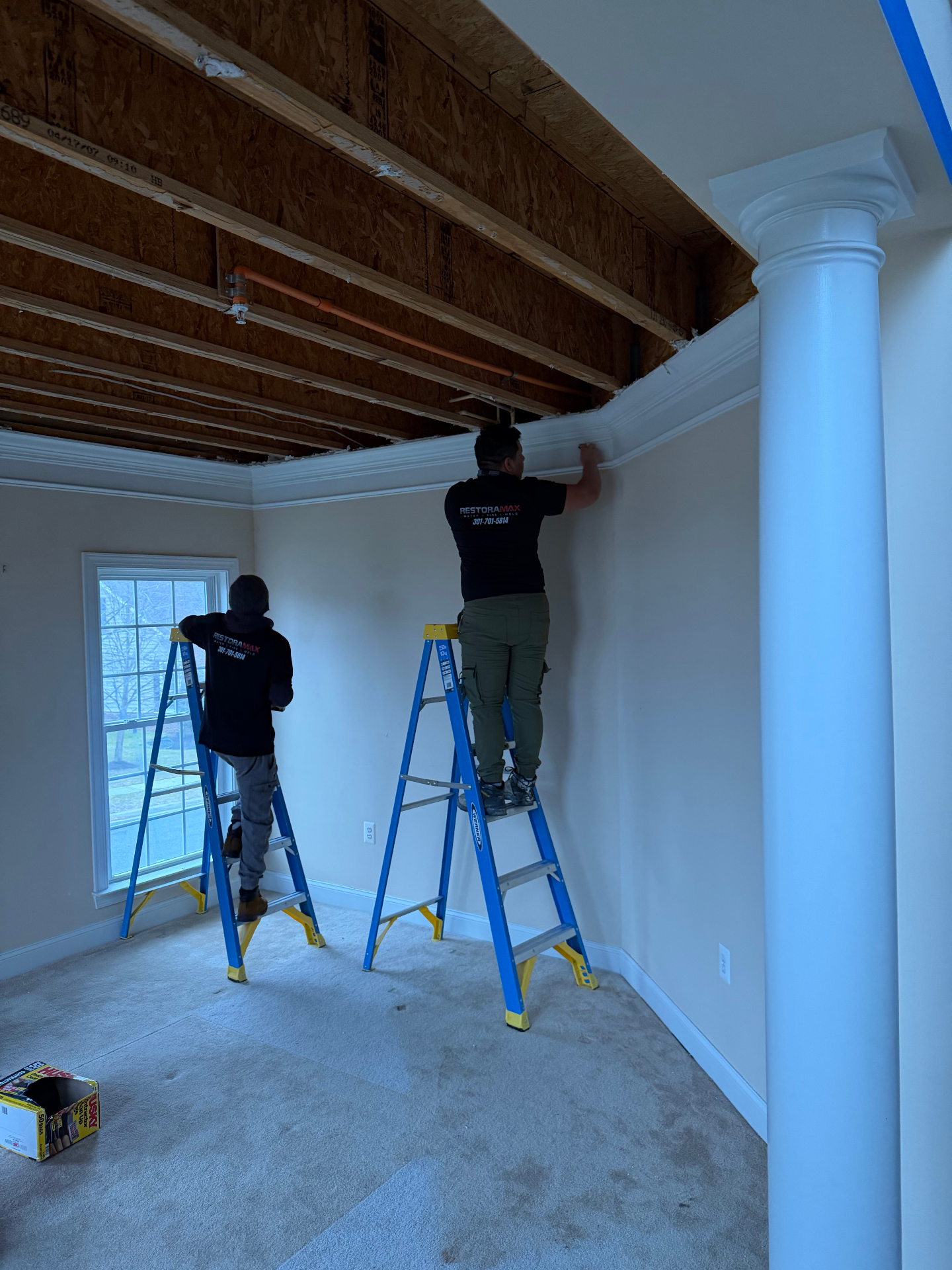 Two technicians on ladders performing ceiling restoration